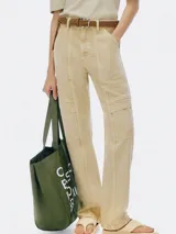 Pantalón cargo de mujer color beige claro, tiro medio/alto, con corte recto y detalles de costuras marcadas en el frente. Presenta bolsillos cargo amplios a la altura de los muslos.