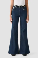 Jeans acampanados de tiro alto, color azul oscuro, con pretina y bolsillos delanteros con estampado de vaca en blanco y negro.
