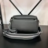 Bandolera negra con correa de tela a rayas grises y cierre superior.