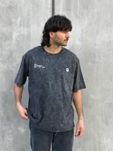 Remera gris con efecto lavado, corte oversize, manga corta y estampado pequeño en el frente.