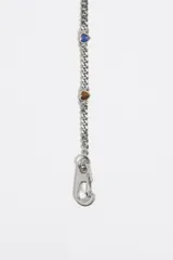 Collar dorado con cadena de eslabones y pequeños dijes de corazones negros.