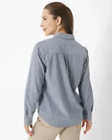 Camisa celeste de manga larga confeccionada en algodón chambray, con cuello clásico, cierre frontal con botones, dos bolsillos de parche en el pecho y corte relajado.