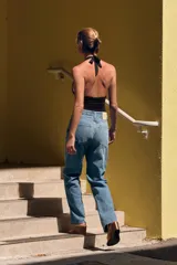 Top negro de cuello halter ajustable con lazadas, espalda descubierta, detalle de aplicación metálica en el delantero y drapeado lateral.