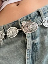 Cinturón plateado tipo cadena con dijes ovalados con diseño de toro.