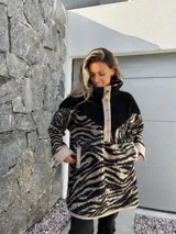 Buzo de polar con cuello alto, cierre de botones a presión y estampado de cebra en tonos beige y negro.