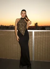 Vestido largo negro con corpiño de encaje floral color nude, cuello halter y falda ajustada con frunces laterales.