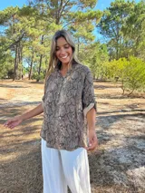 Blusa de manga corta con cuello mao y cierre parcial de botones, con estampado de piel de serpiente en tonos marrones y grises.