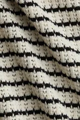 Top de punto con textura a rayas horizontales en blanco y negro. Tiene cuello camisero abierto, mangas cortas y corte holgado.