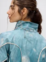 Campera rompevientos estilo biker con capucha desmontable, color celeste con estampado de nubes blancas y detalles en blanco.