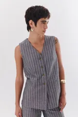 Chaleco gris con finas rayas verticales blancas, con cuello en V, cierre frontal con botones y bolsillos laterales.
