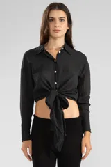 Camisa negra de manga larga con lazo en la cintura y botones nacarados. Confeccionada en algodón.