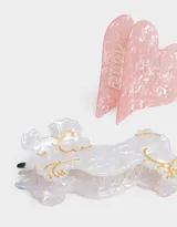 Set de dos broches para el pelo: uno con forma de corazón rosa y otro con forma de caniche blanco con detalles dorados.