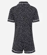 Conjunto de pijama corto negro con lunares blancos y ribetes blancos. Incluye camisa de manga corta con cuello y botones, y short con cintura elástica.
