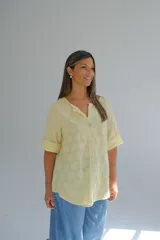 Blusa amarilla con diseño de lunares en relieve, corte acampanado, escote en V con un botón y mangas 3/4 con botón para ajustar el largo.