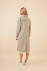 Tapado largo color beige con cuello solapa y corte recto. Cierre frontal con botones, detalles aplicados en la parte delantera, tajo en la espalda y bolsillos ojal con tapa. Con forro. Hecho en Uruguay con tela 100% lana fina sin teñir.