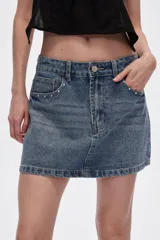 Minifalda de jean azul con lavado medio, corte recto y detalles de strass en bolsillos y laterales.