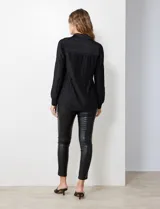 Camisa negra de satén plisado con cuello con solapa y abertura central con botones.