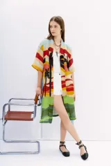 Kimono largo de lino con estampado de paisaje playero con palmeras, en tonos celeste, amarillo, rojo, verde y negro. Tiene mangas amplias, bolsillos al frente y lazo en la cintura.