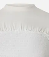 Blusa color crema con cuello redondo y mangas cortas. Presenta un recorte texturizado en el busto y está confeccionada en algodón.