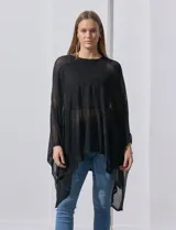 Poncho negro de tejido calado con lurex, terminación asimétrica y cuello redondo.