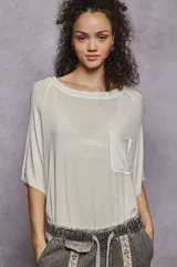 Remera manga corta color blanco hueso, de corte holgado y tejido liviano. Presenta cuello redondo y bolsillo de parche en el pecho.