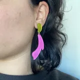 Aros largos de diseño tribal en colores fucsia y amarillo, con forma fluida.