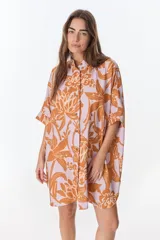 Vestido camisero corto con estampado floral en tonos naranja y lila, cuello mao, manga corta con puño, botones frontales y tajos laterales.