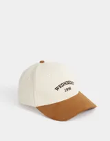 Gorra de béisbol bicolor, con cuerpo de canvas color crema y visera de gamuza color marrón. Tiene bordado frontal con la palabra "Wednesday" y el número "1996".