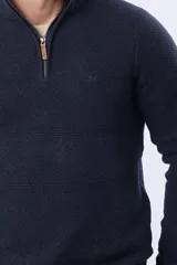 Buzo de punto color azul marino, con cuello alto y cierre frontal parcial con detalle de cuero. Presenta un diseño texturizado con franjas horizontales.