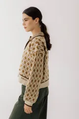 Sweater de punto color beige con diseño de rombos marrones, cuello polo con botones y mangas largas abullonadas.