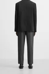 Pantalón slim fit negro confeccionado en tejido con elasticidad en ambas direcciones. Cuenta con bolsillos frontales y traseros de vivo con botón. Cierre frontal con cremallera y botón.