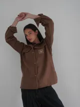 Camisa gris de lana con corte clásico, cuello camisero, cierre frontal con botones de cuerno y dos bolsillos de parche en el pecho.