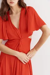 Vestido midi color ladrillo, con escote en V, mangas cortas acampanadas, nudo en la cintura y aberturas laterales.