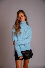 Sweater verde esmeralda de punto trenzado, con cuello alto y mangas largas.