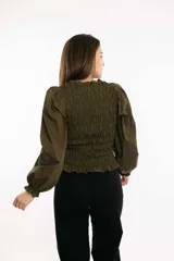 Blusa blanca de algodón con frunces tipo smock en el cuerpo, cuello redondo y mangas largas abullonadas con puños elásticos.