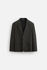 Blazer regular fit color gris oscuro, confeccionada en tejido con estructura. Cuello con solapas de muesca y manga larga. Bolsillos de solapa en cadera. Cierre frontal de botonadura.