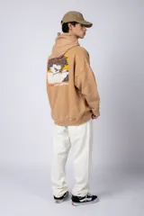 Buzo canguro color ocre con capucha y cordones negros, de corte oversize y confeccionado en tela de algodón friza con teñido artesanal y estampa circular en el pecho.