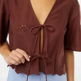 Blusa marrón con escote en V, mangas cortas y lazos para atar en el frente.