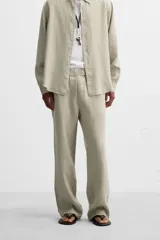 Pantalón negro regular fit confeccionado en tejido de lino. Cintura ajustable con cordón interior, bolsillos frontales y detalle de bolsillos traseros de vivo.