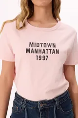 Remera rosa de algodón con estampado negro con la frase "Midtown Manhattan 1997".