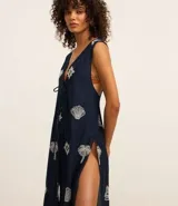 Salida de playa tipo bata larga sin mangas, color azul marino, con bordado laise de caracolas y lazo delantero. Confeccionada en algodón BCI.