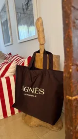 Bolso tote marrón con asas cortas y logo de la marca Agnes Lenoble estampado en blanco.