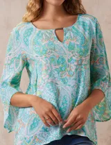 Blusa de gasa estampada marca Ruby Rd. con cuello redondo, escote en V con aplique metálico, delantera con sobre capa y terminación asimétrica. Manga ¾ amplia.