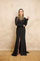 Vestido largo negro con cuello mao bordado con lentejuelas doradas, manga larga y tajo lateral con detalle de encaje.