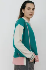 Buzo tipo polo de punto con rayas verticales en tonos beige, marrón y rosa. Tiene cuello polo marrón, cierre parcial con botones amarillos y terminaciones acanaladas en puños y ruedo.