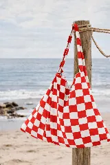 Bolso de playa con estampado a cuadros rojos y blancos, con asas de tela a juego.