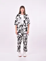 Pantalón babucha de tela estampada con hojas en tonos rosa, naranja y azul, con cintura elastizada y lazo para ajustar.
