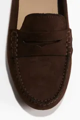 Mocasines marrones de tejido cepillado con lengüeta decorativa y costura tradicional adelante. Forro en lona de algodón y suelas de guijarros.