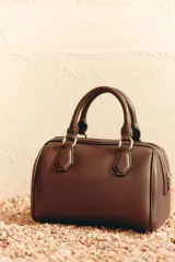 Bolso marrón formato city con asa doble de mano con detalles metálicos y correa interior extraíble en tejido canvas con posición bandolera. Bolsillo interior con cierre mediante cremallera metálica.