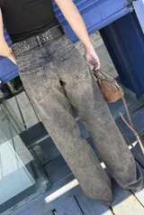 Pantalón jean azul oscuro, de corte wide leg y tiro medio. Presenta detalles de costuras diagonales en la parte superior.